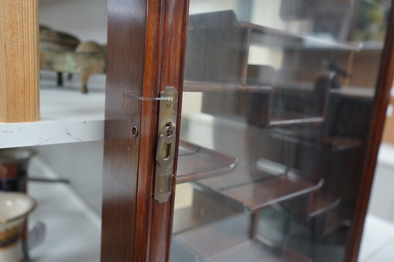 A narrow Chinese hardwood display cabinet, fitted with decorative shaped hardwood shelving, 82.5cm high x 53cm wide at base x 10.5cm deep at base. Condition - marks to wood when cello tape has been, other wise good